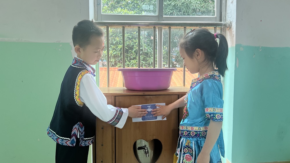 燎原幼兒園小朋友們進行節(jié)約用水情景劇，將節(jié)約用水標識張貼在打水處1.jpg